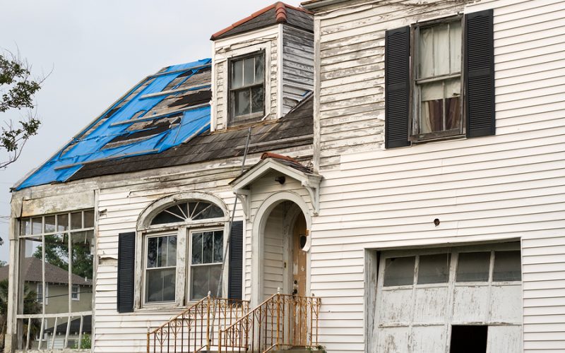nearly two post-katrina abandoned houses are found throughout orleans - this one still has the tattered remains of a fema blue roof and some of the vinyl siding that wasn't blown away