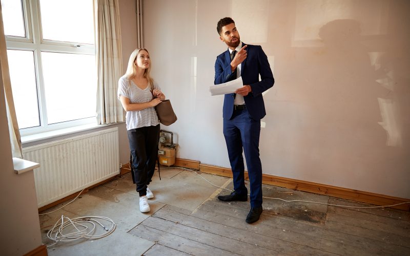 Female First Time Buyer Looking At House Survey With Realtor