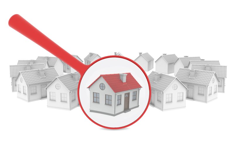 Choosing home. Several houses and a magnifying glass. Isolated render on a white background